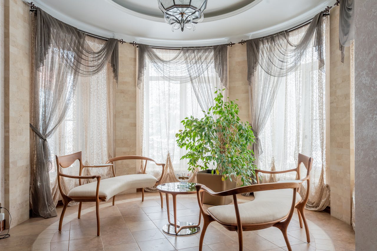 A bright and sophisticated sitting area featuring elegant furniture and natural light filtering through sheer curtains.
