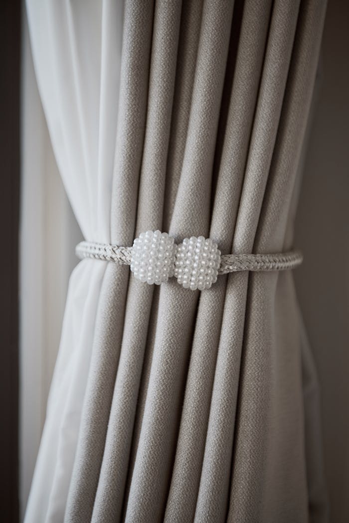 Luxurious gray curtains held by a decorative pearl tieback, adding elegance to any room.